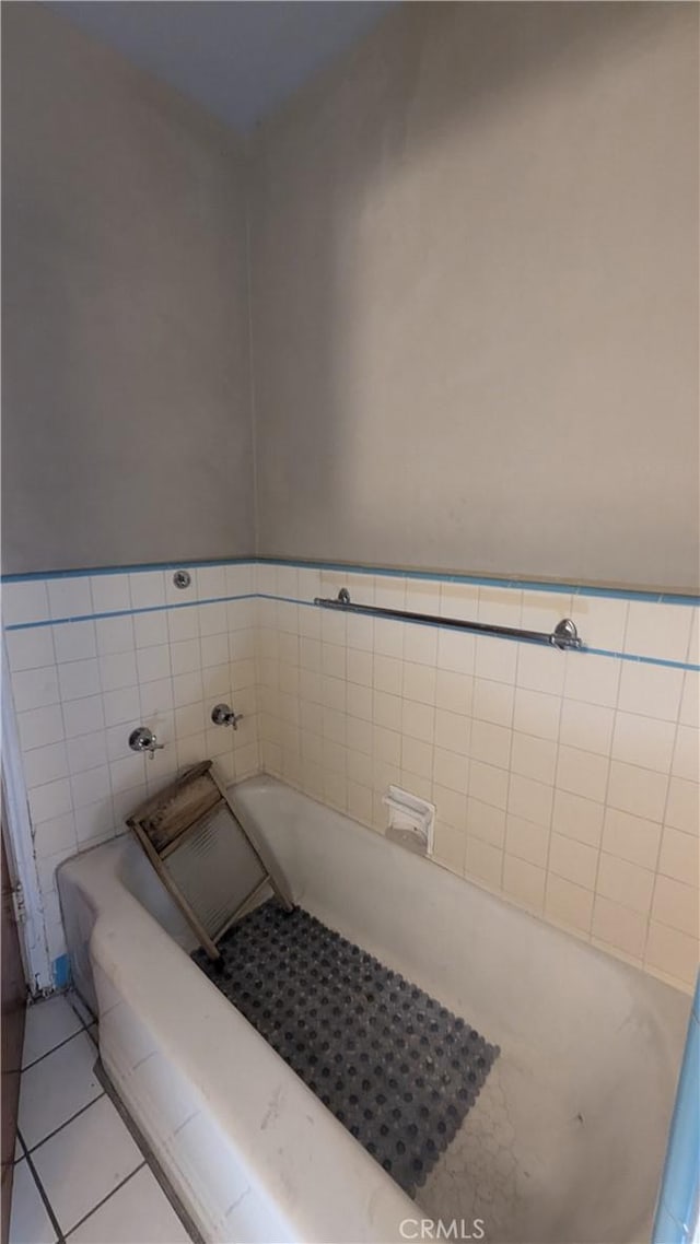 bathroom featuring tile patterned floors, a bath, and tile walls