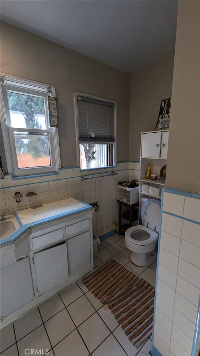 bathroom with tile patterned flooring, vanity, toilet, and tile walls