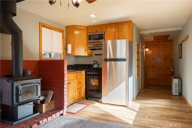 kitchen with a wood stove, light hardwood / wood-style flooring, and stainless steel appliances