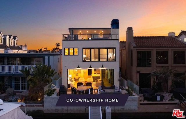 back house at dusk with a balcony