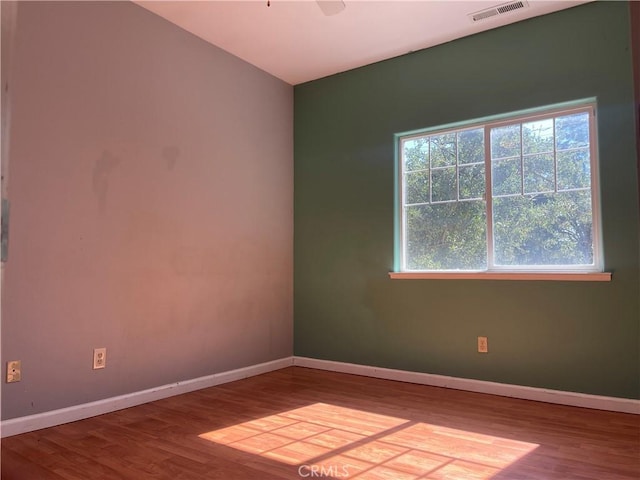 empty room featuring a wealth of natural light and wood-type flooring