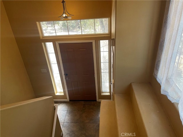 entrance foyer with dark tile patterned floors and a healthy amount of sunlight