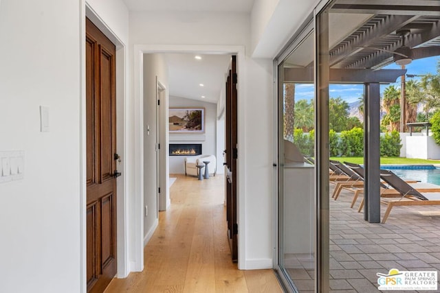 corridor featuring vaulted ceiling and light hardwood / wood-style floors