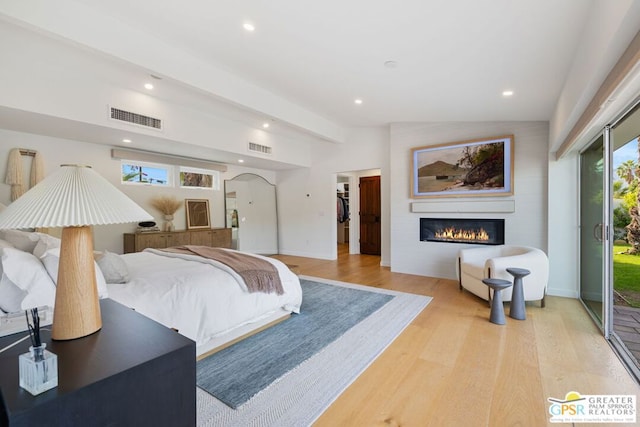 bedroom featuring a large fireplace, lofted ceiling, light hardwood / wood-style floors, and access to outside