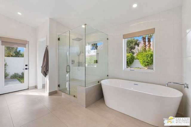 bathroom with tile walls, tile patterned floors, shower with separate bathtub, and a healthy amount of sunlight