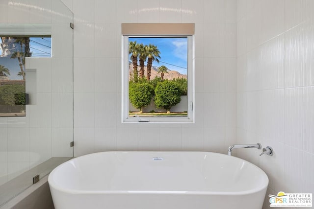 bathroom featuring tile walls and a washtub