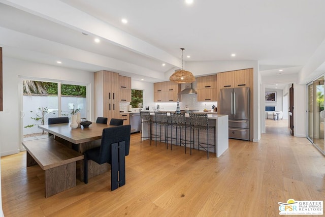 dining space with lofted ceiling with beams and light wood-type flooring