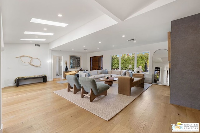 living room with a skylight and light hardwood / wood-style flooring