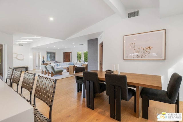 dining space with light hardwood / wood-style floors and vaulted ceiling with beams