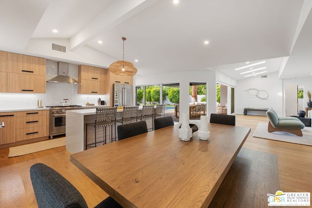 dining room featuring light hardwood / wood-style flooring and lofted ceiling with beams