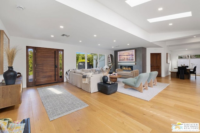 living room with a skylight and light wood-type flooring