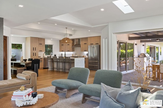 living room with light hardwood / wood-style flooring and vaulted ceiling with skylight