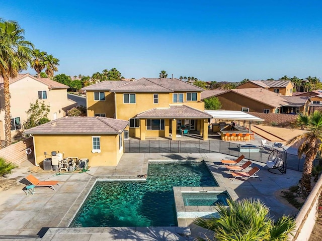 back of house with central AC unit, a gazebo, a patio area, and a pool with hot tub