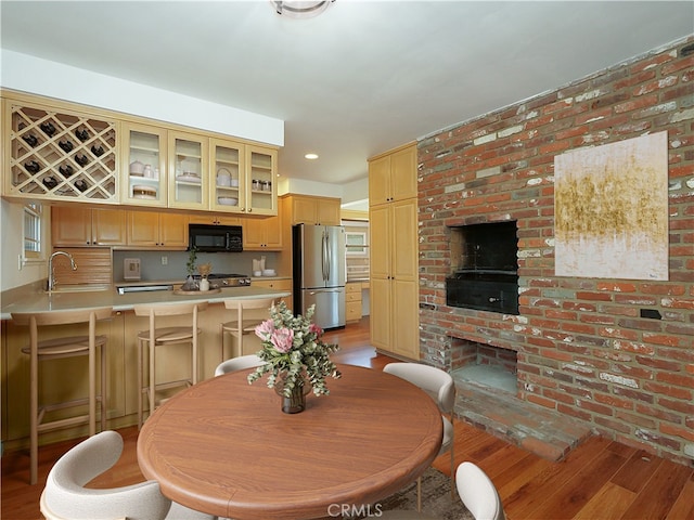 dining room with sink, brick wall, and light wood-type flooring