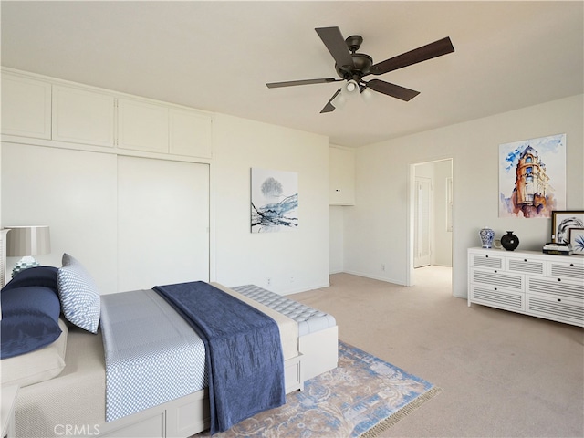 bedroom featuring ceiling fan, a closet, and light colored carpet