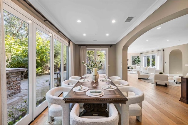 dining area with light hardwood / wood-style floors, ornamental molding, and french doors