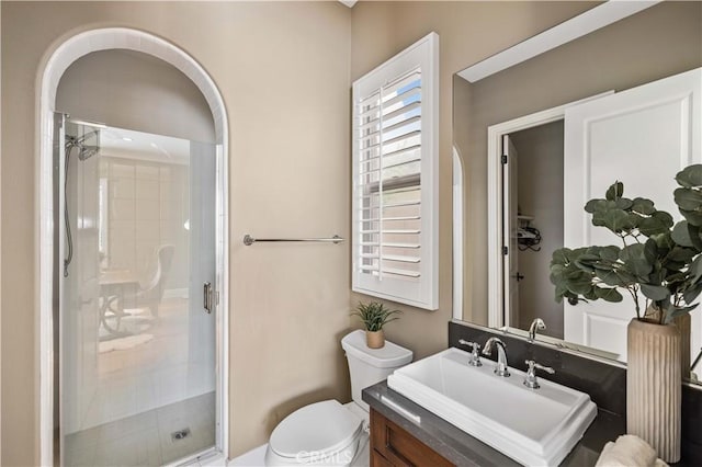 bathroom featuring a shower with door, vanity, and toilet