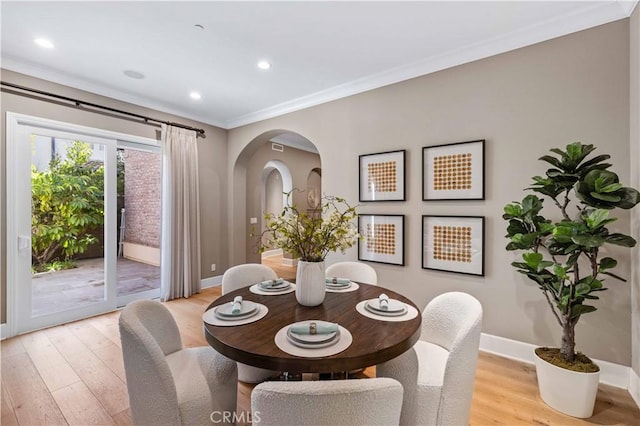 dining area with crown molding and light hardwood / wood-style floors