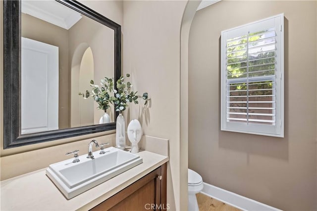 bathroom with hardwood / wood-style floors, vanity, toilet, and ornamental molding