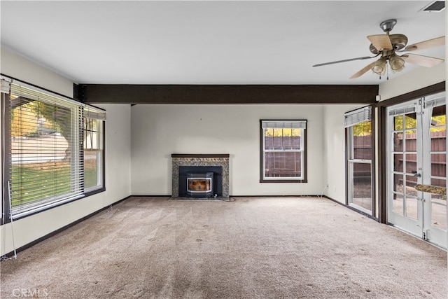 unfurnished living room featuring beam ceiling, carpet flooring, a healthy amount of sunlight, and ceiling fan