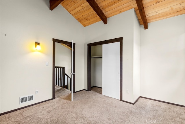 unfurnished bedroom featuring beam ceiling, high vaulted ceiling, wooden ceiling, a closet, and light colored carpet