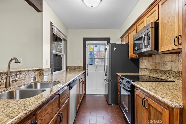 kitchen with appliances with stainless steel finishes, light stone countertops, sink, and dark hardwood / wood-style flooring