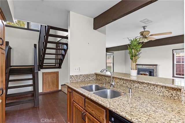 kitchen featuring beam ceiling, dark wood-type flooring, sink, light stone counters, and ceiling fan