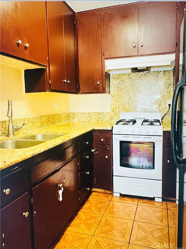 kitchen with white range with gas stovetop, sink, and tasteful backsplash