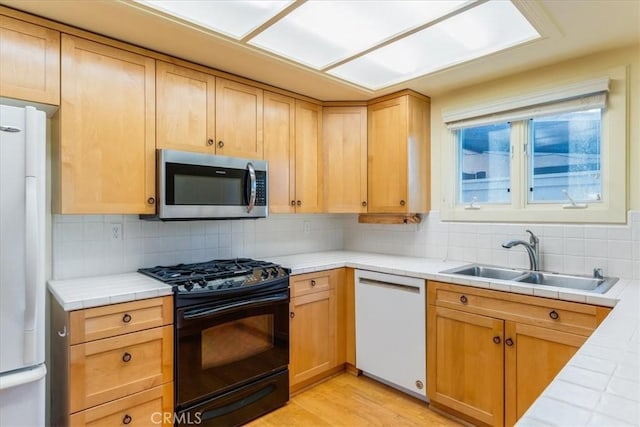 kitchen with white appliances, sink, decorative backsplash, tile counters, and light hardwood / wood-style floors