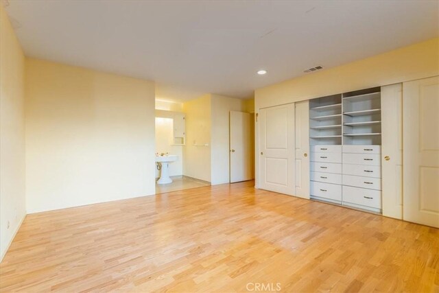 unfurnished bedroom with ensuite bath and light hardwood / wood-style flooring