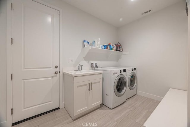 washroom featuring cabinets, independent washer and dryer, and sink