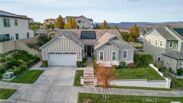 view of front of house with a front yard, a garage, a mountain view, and solar panels