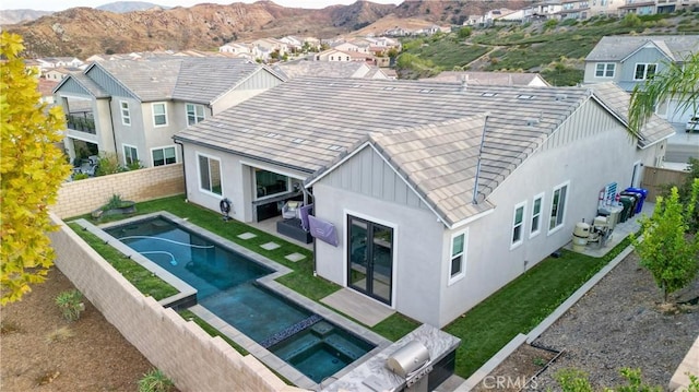 rear view of house with a swimming pool with hot tub and a mountain view