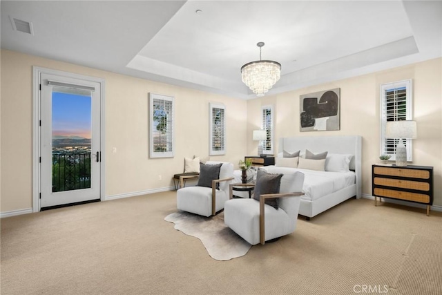 bedroom featuring a raised ceiling, access to exterior, and light carpet