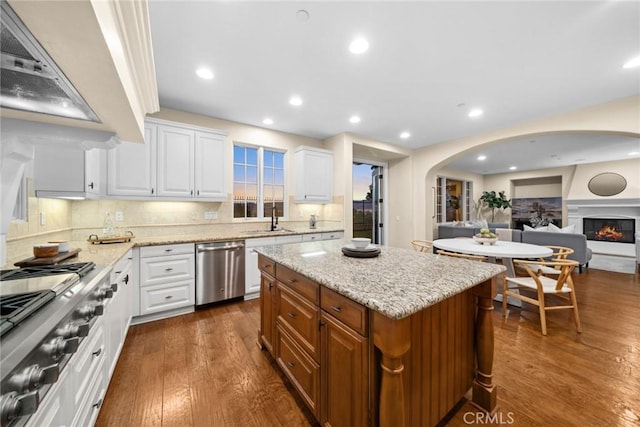 kitchen with white cabinets, appliances with stainless steel finishes, tasteful backsplash, a kitchen island, and dark hardwood / wood-style flooring