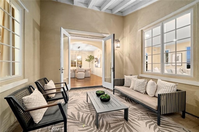 living area featuring hardwood / wood-style floors, beamed ceiling, and french doors