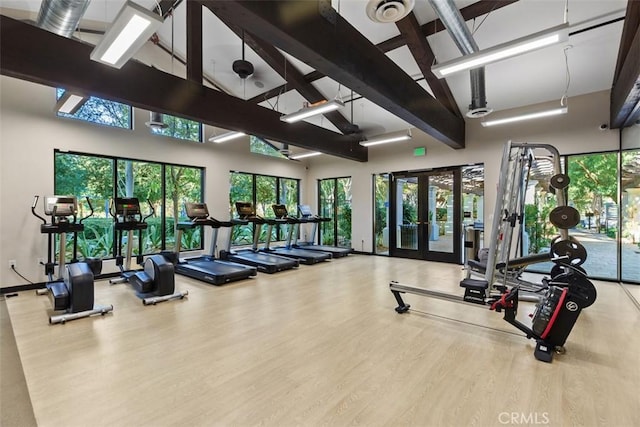 workout area with hardwood / wood-style floors, a towering ceiling, and french doors