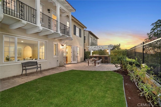 yard at dusk featuring a pergola, a balcony, and a patio area