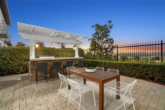 patio terrace at dusk with a pergola and a bar