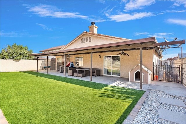 rear view of property featuring ceiling fan, a patio area, outdoor lounge area, and a lawn