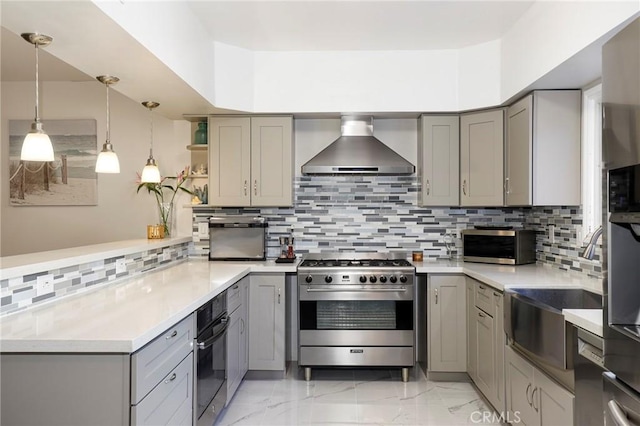 kitchen featuring kitchen peninsula, gray cabinets, stainless steel appliances, backsplash, and wall chimney range hood