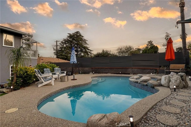 pool at dusk with a patio area