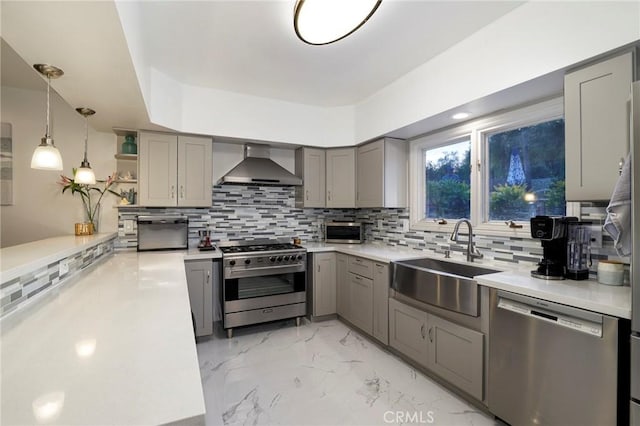 kitchen featuring appliances with stainless steel finishes, wall chimney exhaust hood, tasteful backsplash, sink, and gray cabinetry