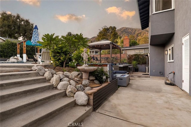 patio terrace at dusk featuring a gazebo and a mountain view