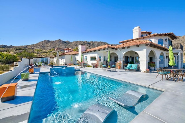 view of swimming pool featuring pool water feature, a mountain view, and a patio