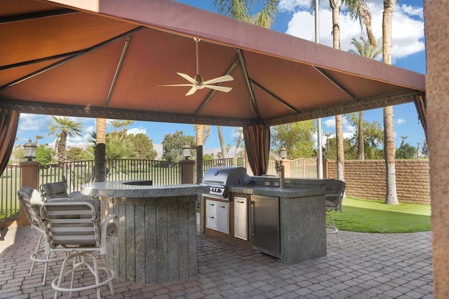 view of patio / terrace featuring a gazebo, a bar, area for grilling, and ceiling fan