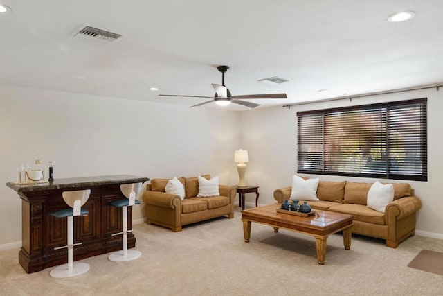 living room with ceiling fan, light colored carpet, and indoor bar