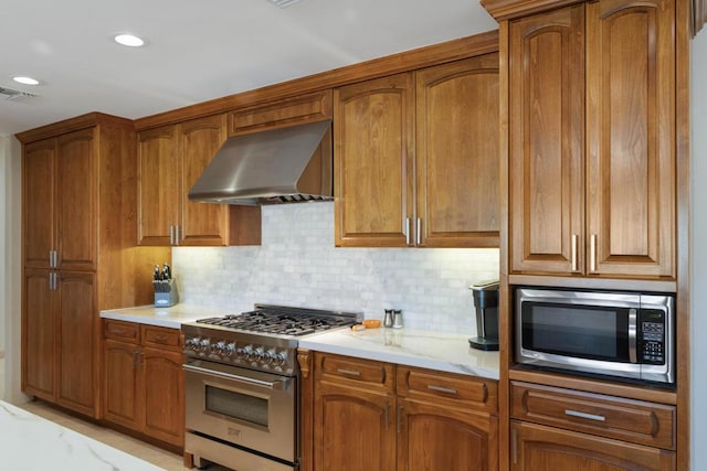 kitchen featuring decorative backsplash, appliances with stainless steel finishes, light stone counters, and wall chimney exhaust hood