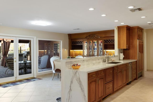 kitchen with french doors, sink, light stone countertops, light tile patterned flooring, and kitchen peninsula