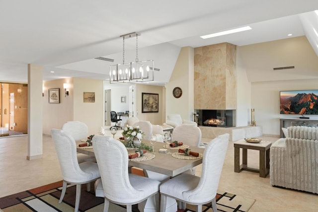 tiled dining room with vaulted ceiling, a fireplace, and a chandelier